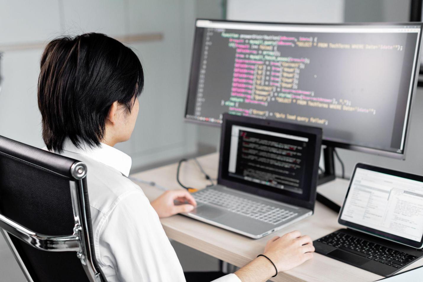 Indie game developer working with code across multiple computer screens