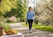 Woman walking through a sunlit park in spring while carrying a water bottle