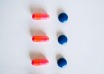Pink capsules and round blue tablets arranged on a white background