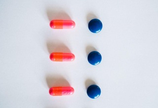 Pink capsules and round blue tablets arranged on a white background