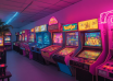 Arcade and pinball machines under pink and blue neon lighting.