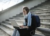Woman using a laptop while seated on outdoor stone steps
