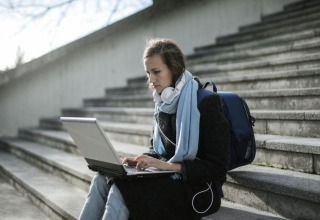 Woman using a laptop while seated on outdoor stone steps