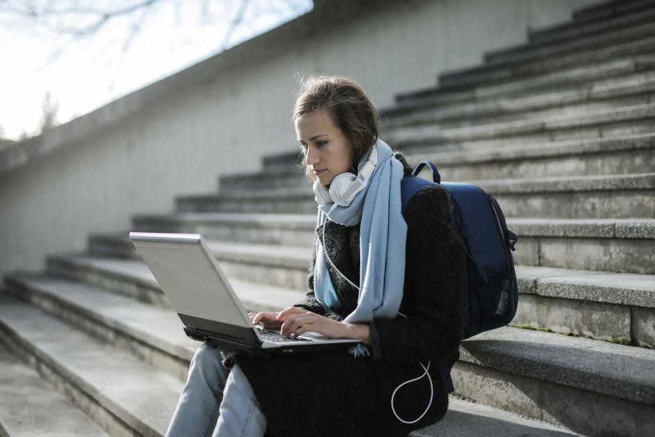 Woman using a laptop while seated on outdoor stone steps