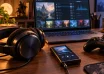 Headphones, a portable music player and a game controller beside a laptop showing an illustrated soundtrack library.