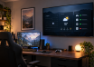 Wall-mounted spare TV showing calendar, weather and server-status panels above a gaming desk