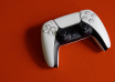 White and black PlayStation 5 DualSense controller on a red background