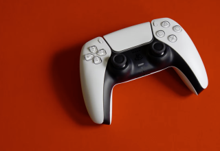 White and black PlayStation 5 DualSense controller on a red background
