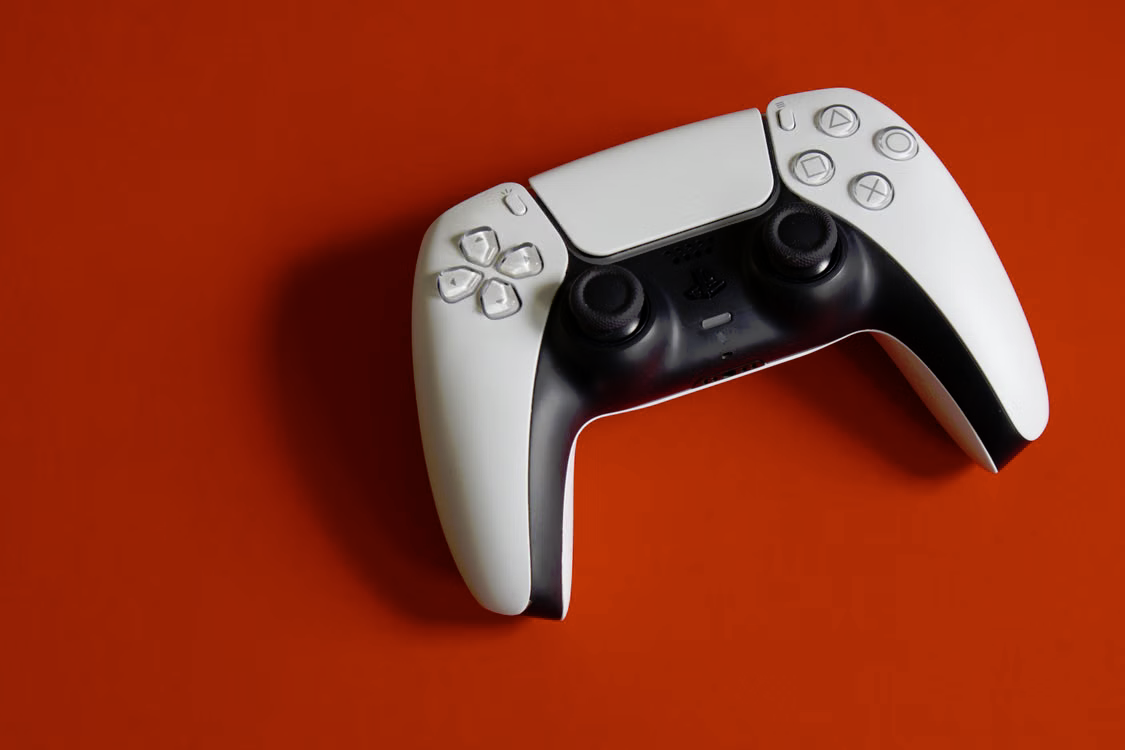 White and black PlayStation 5 DualSense controller on a red background